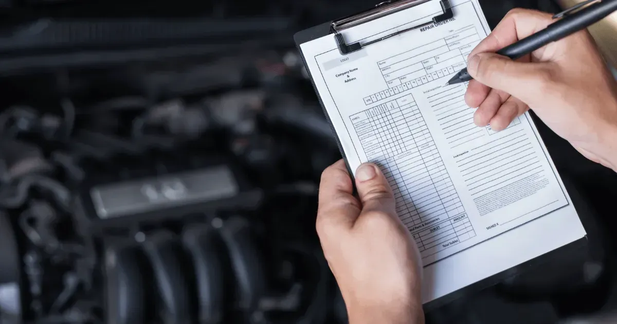 An auto technician filling out a detailed vehicle check sheet clipboard during a pre-purchase car inspection.