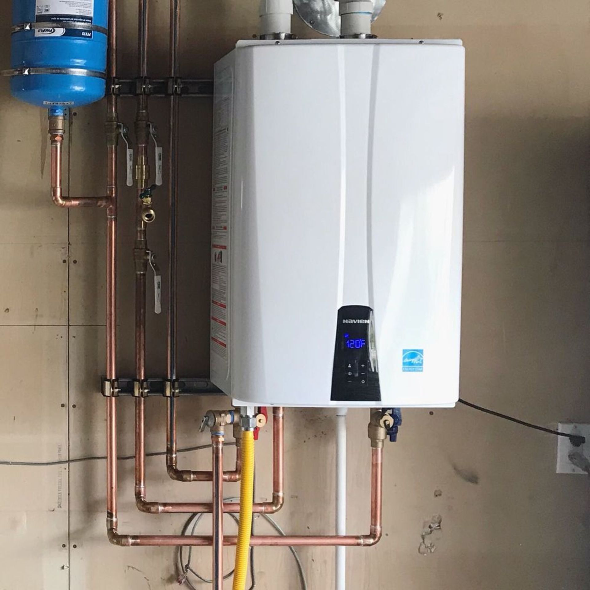 a white water heater is attached to a wall with copper pipes