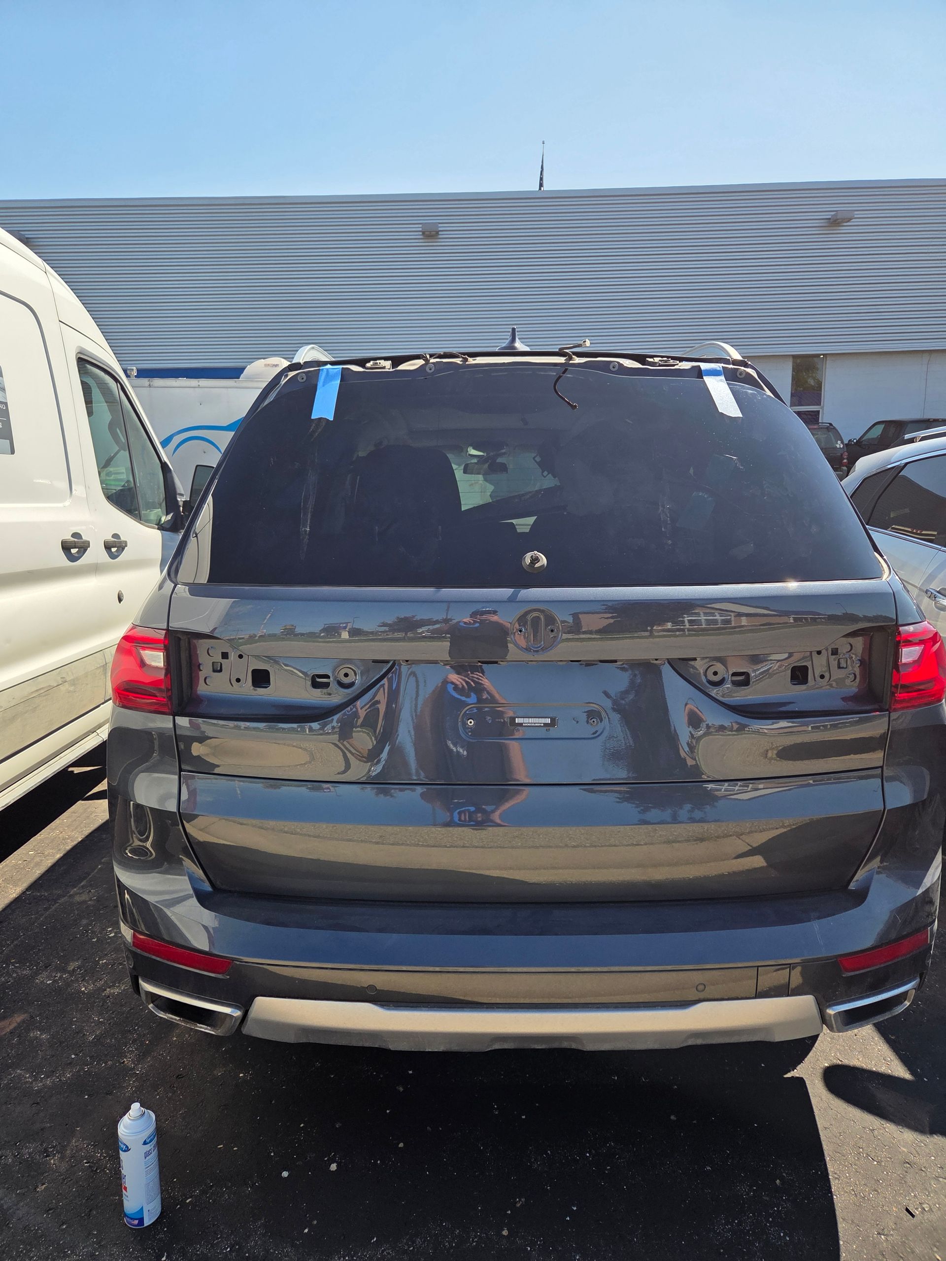 Detailer polishing a car windshield with a blue buffer in an auto shop