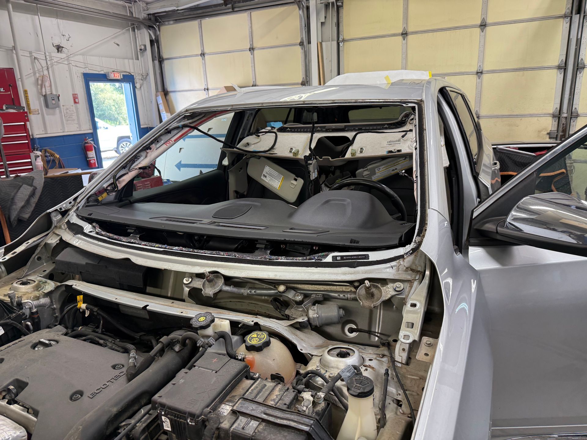 Blue car with orange suction-cup mounts on the rear window at an indoor auto shop