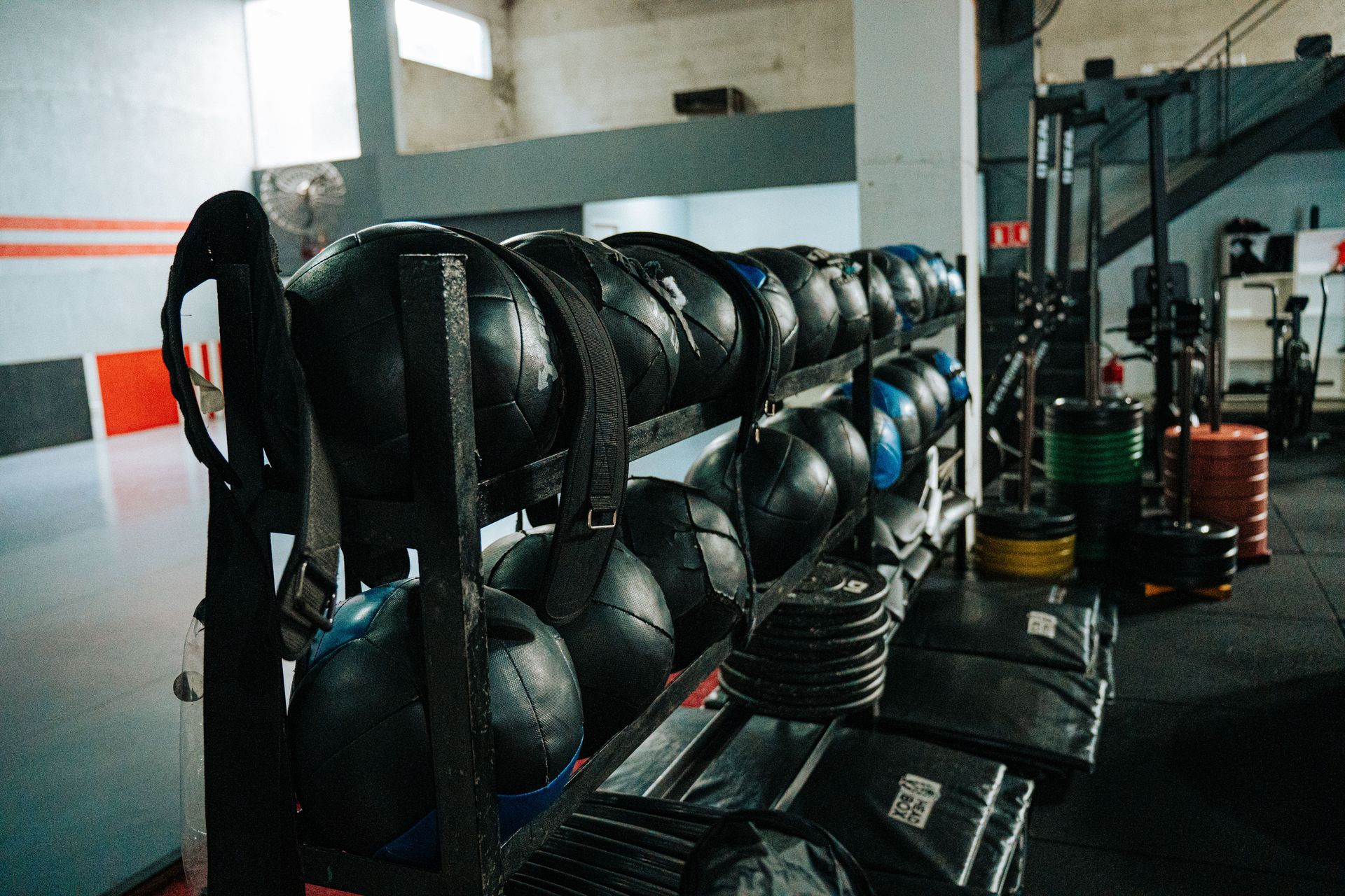 Stacks of kettlebells and medicine balls in a gym storage area