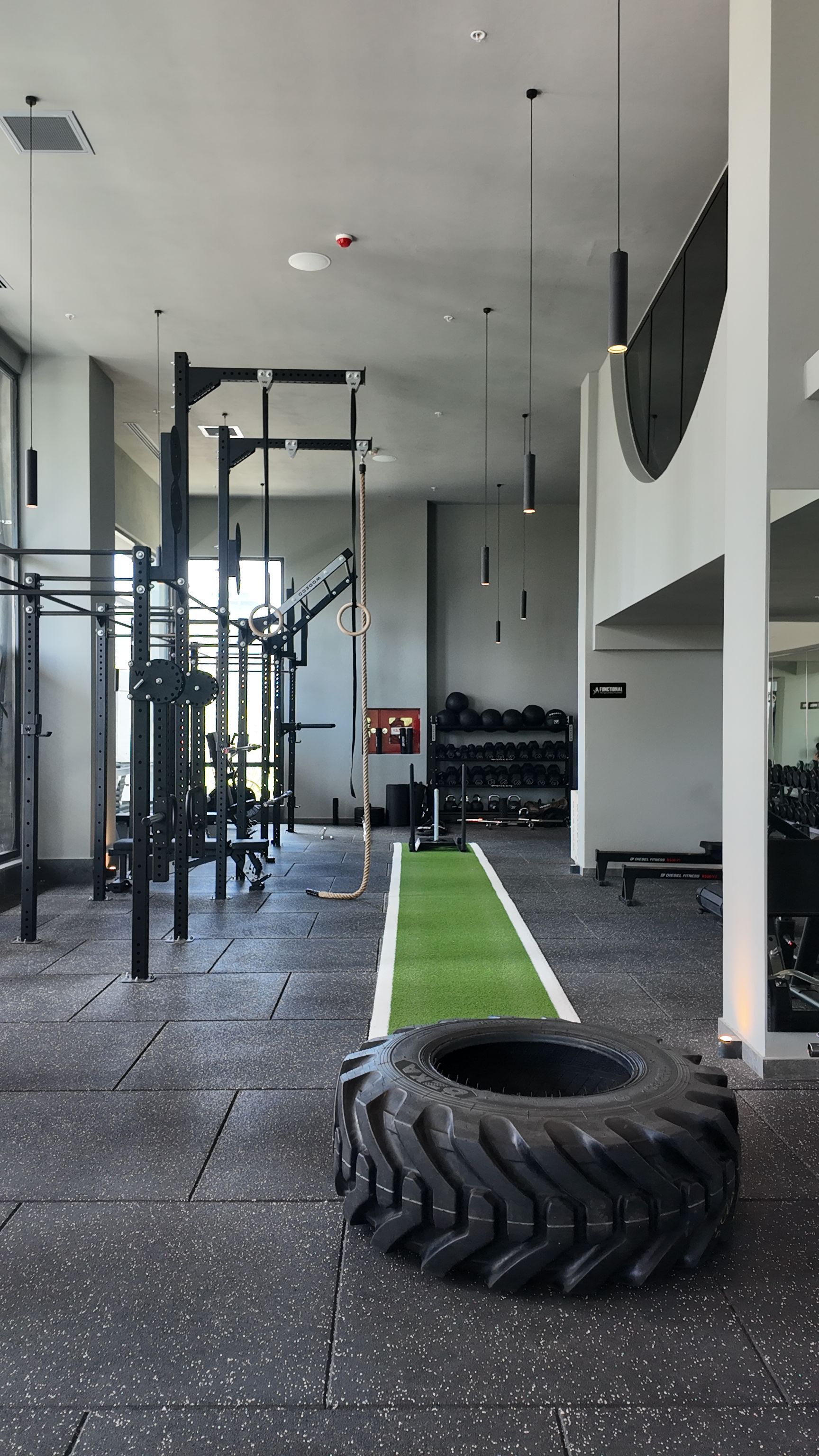 Indoor gym with turf lane, tire, and weight equipment in a bright training space