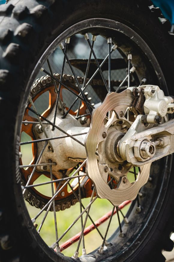 Primo piano della ruota posteriore, del disco del freno e della catena di una moto da cross