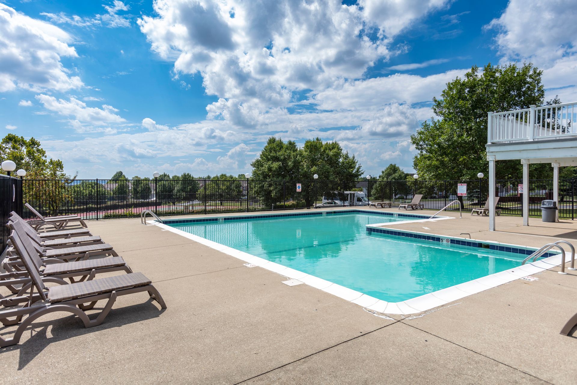 Outdoor swimming pool with lounge chairs and fenced sundeck