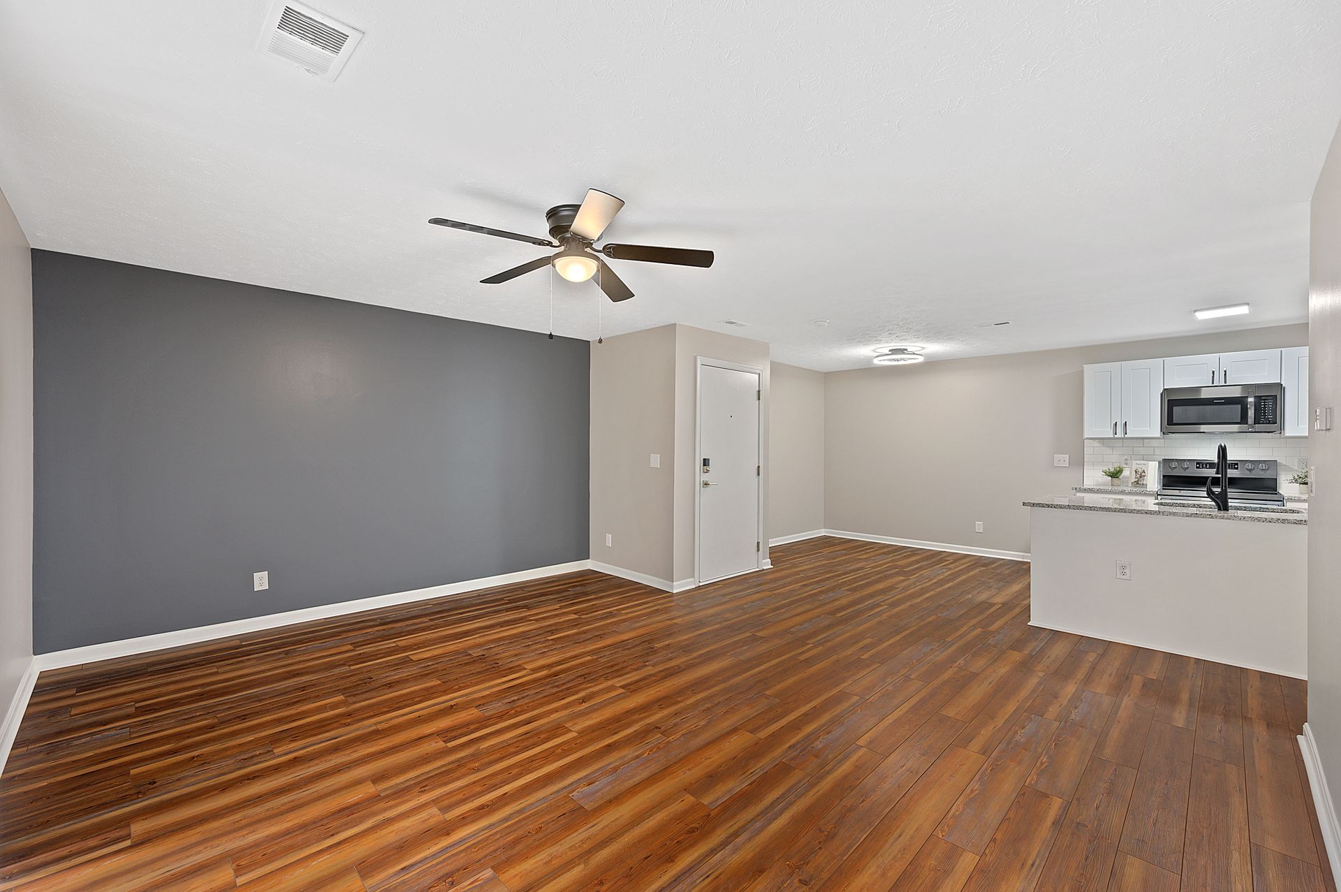 an empty living room with hardwood floors and a ceiling fan .