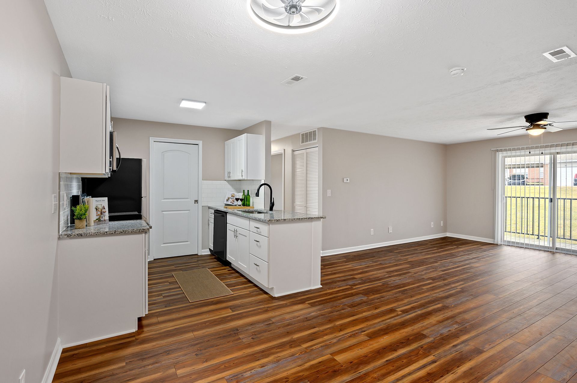 a living room with hardwood floors and a kitchen in a house .