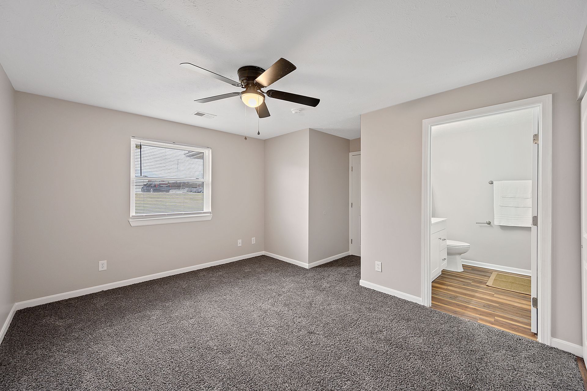An empty bedroom with a ceiling fan and a window .