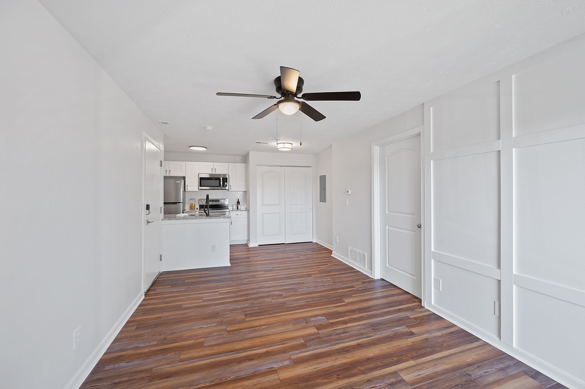 Spacious apartment living room with ceiling fan and hardwood-style flooring