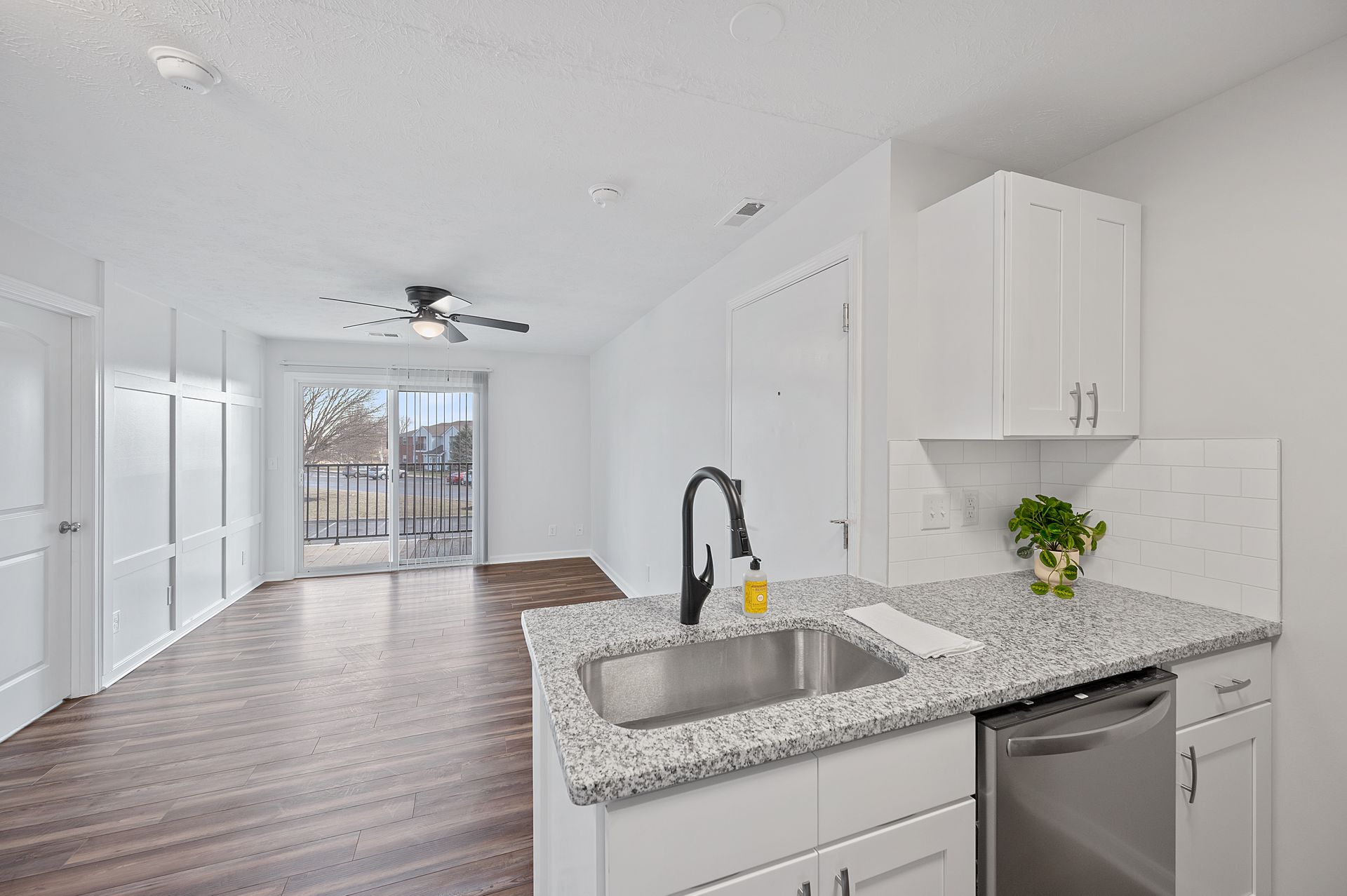 Open kitchen with granite countertops and hardwood-style flooring in apartment