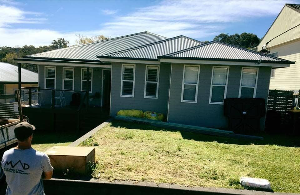 A Man Standing in Front of a House Wearing a Shirt — Mad About Metal Roofing & Guttering PTY LTD in Newcastle, NSW