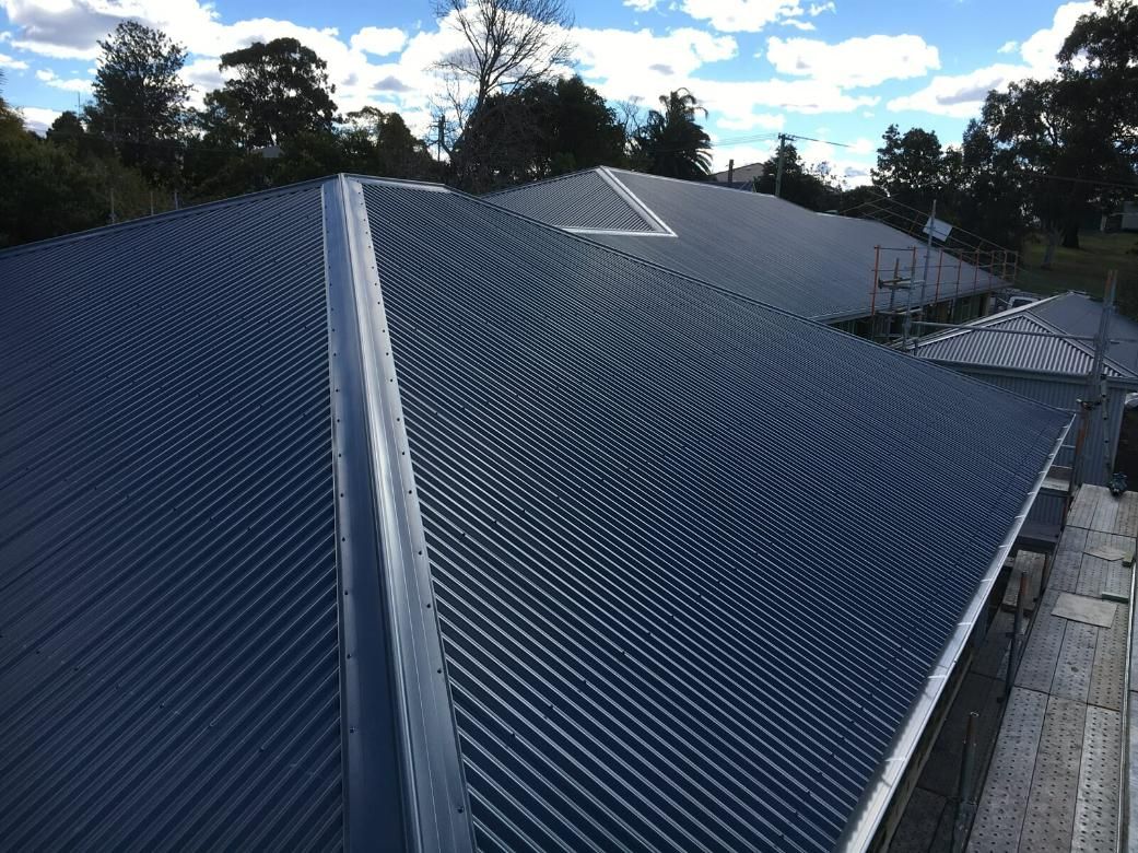 A Close up Of A Blue Roof with Trees In The Background — Mad About Metal Roofing & Guttering PTY LTD in Newcastle, NSW
