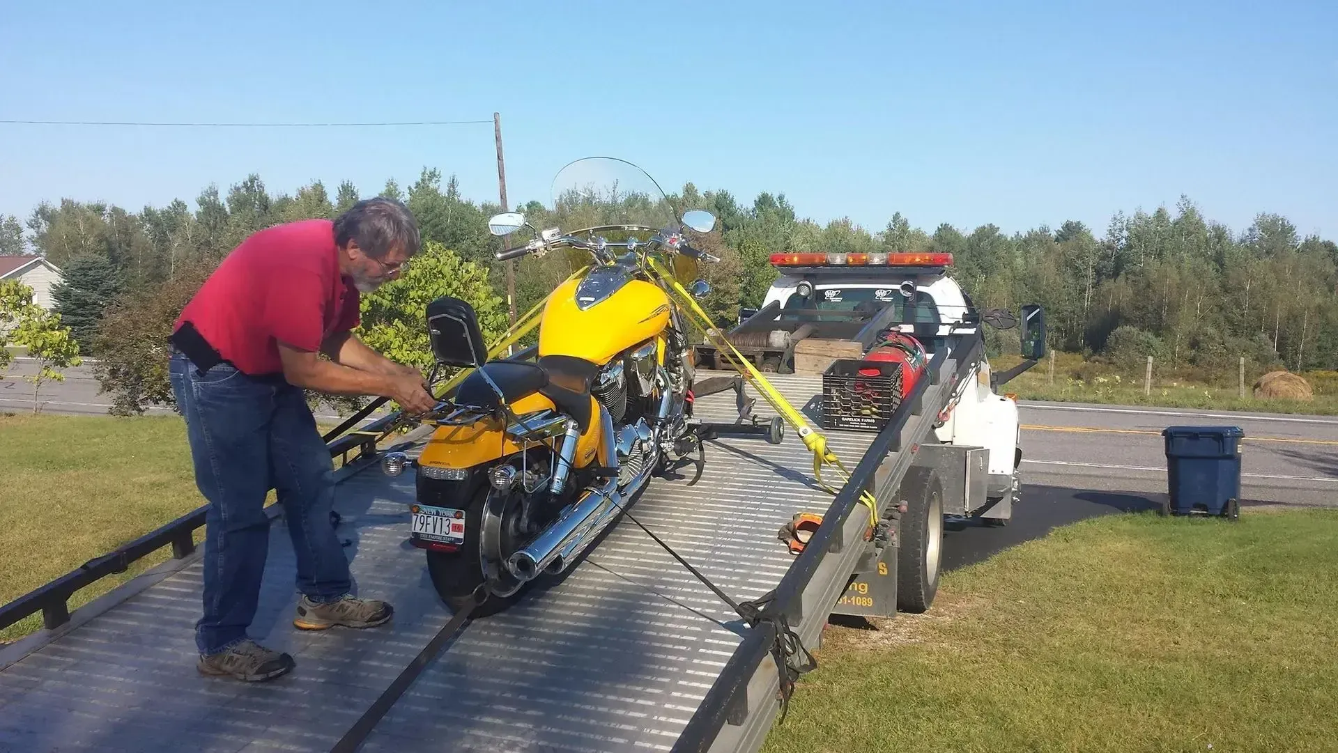 A yellow motorcycle is being towed by a tow truck