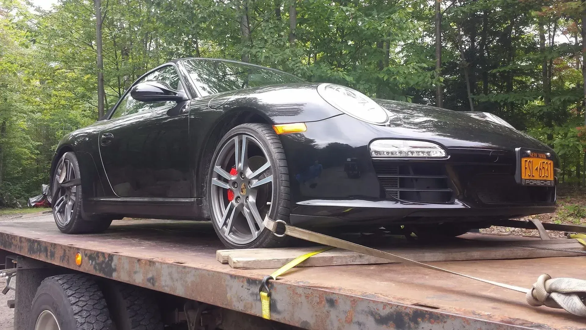 A black sports car is sitting on top of a flatbed truck.