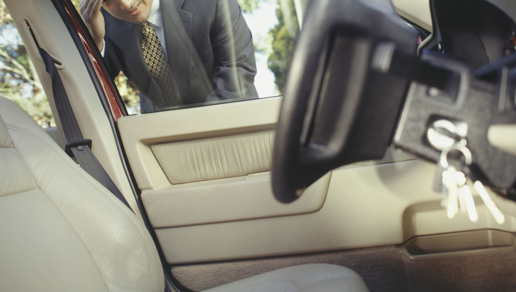 A man in a suit and tie is sitting in the driver 's seat of a car.