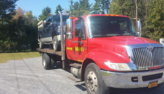 A black tow truck is parked on the side of the road.