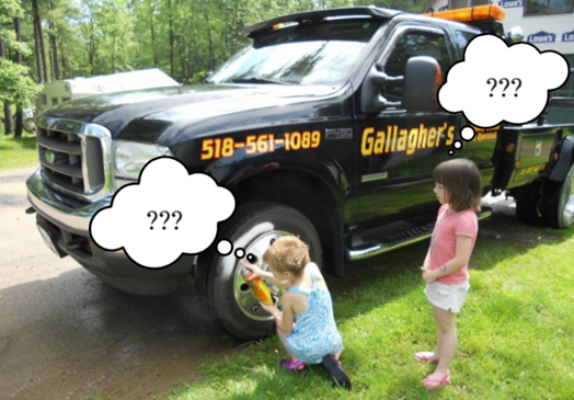 Two little girls looking at a gallagher 's tow truck