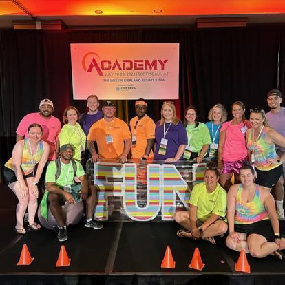 A group of people wearing bright athletic clothes posing in front of a colorful
