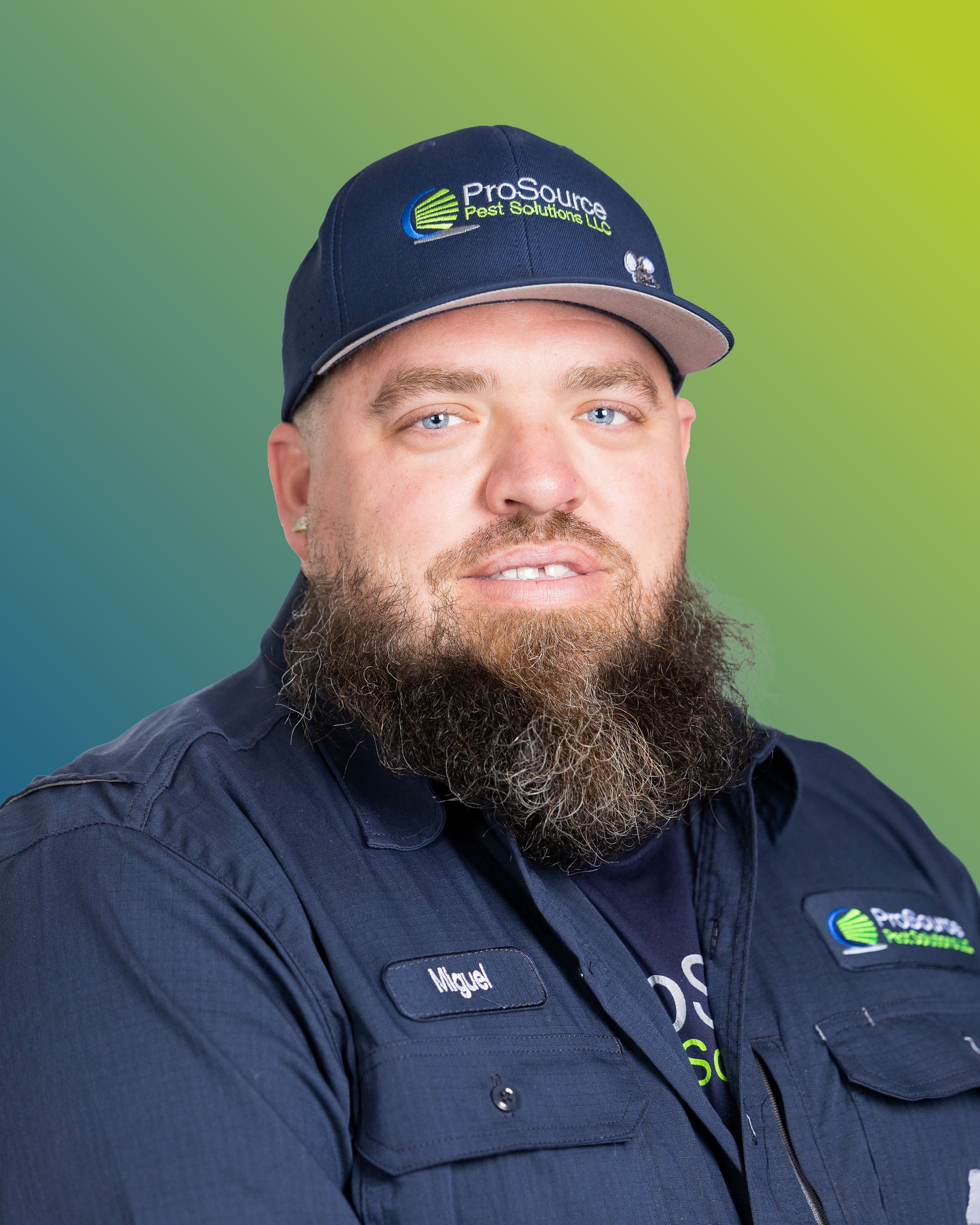 A man with a beard wearing a dark blue uniform shirt and a ProSolve cap against a blue and green gradient background.