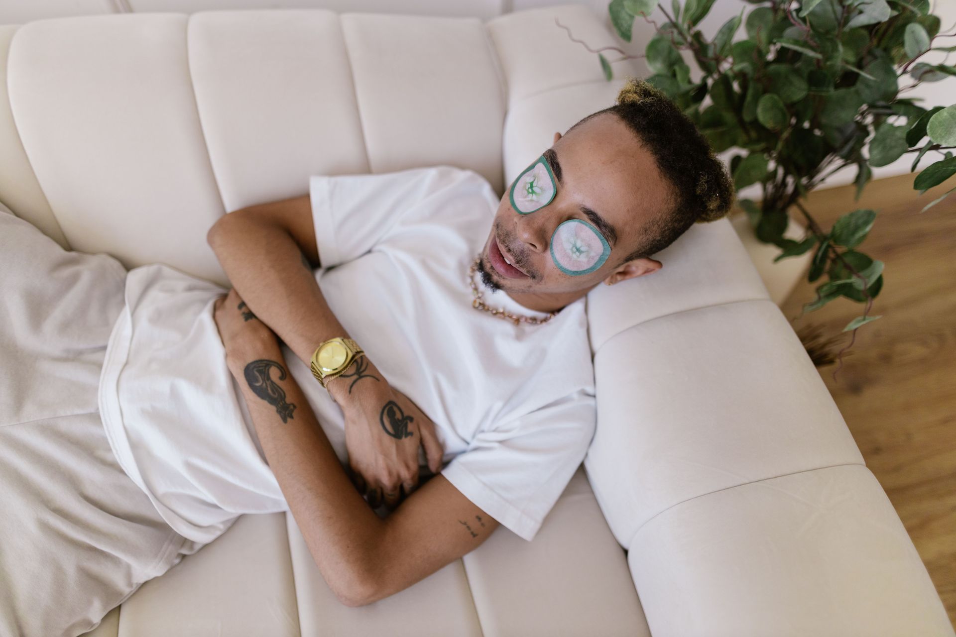 Person lying on a white couch with arms crossed, wearing glasses and a white shirt, smiling.