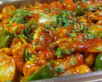 Vegetable Manchurian: colorful dish with vegetables in red sauce, garnished with cilantro.