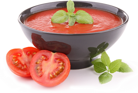 Bowl of tomato soup with basil, sliced tomatoes on the side.