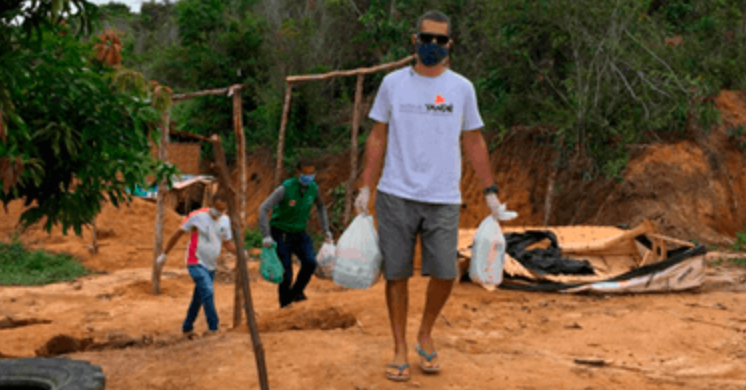 Um homem usando máscara carrega uma sacola de comida.