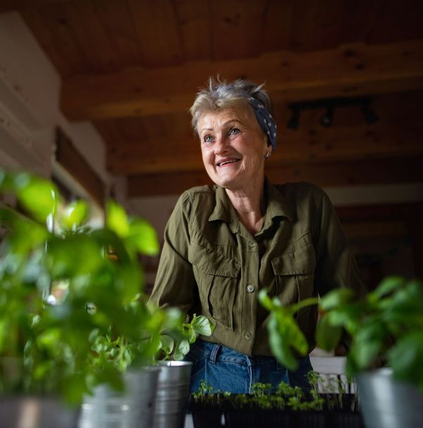 A woman is standing in front of a table with potted plants.