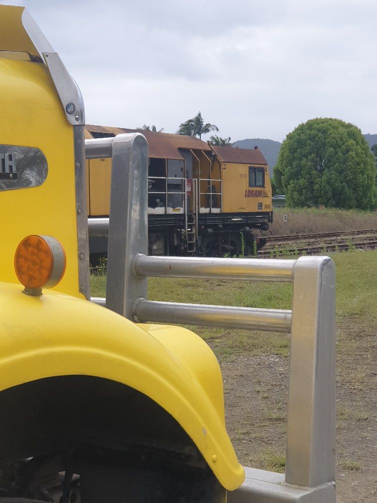 Yellow Vehicle in Foreground, With Silver Rails and a Train — Taree & Mid Coast Water Cartage in Hillville, NSW