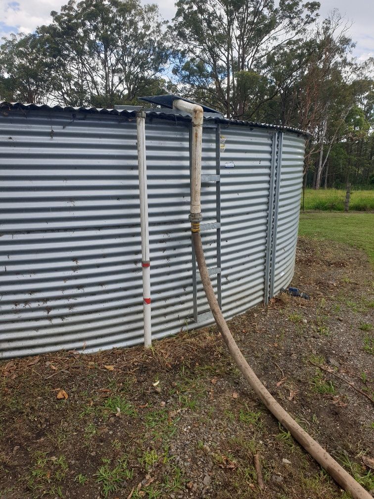 Corrugated Metal Water Tank With a Hose Attached — Taree & Mid Coast Water Cartage in Hillville, NSW