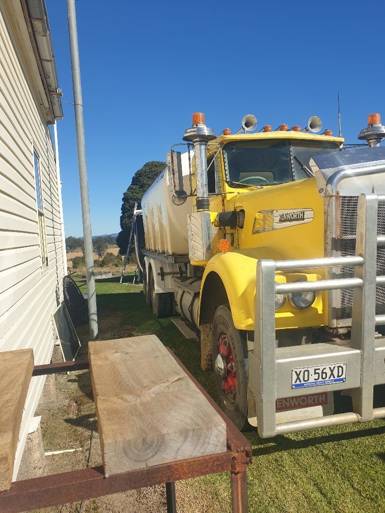 Yellow Tow Truck Parked Beside a Building on a Grassy Lot — Taree & Mid Coast Water Cartage in Hillville, NSW