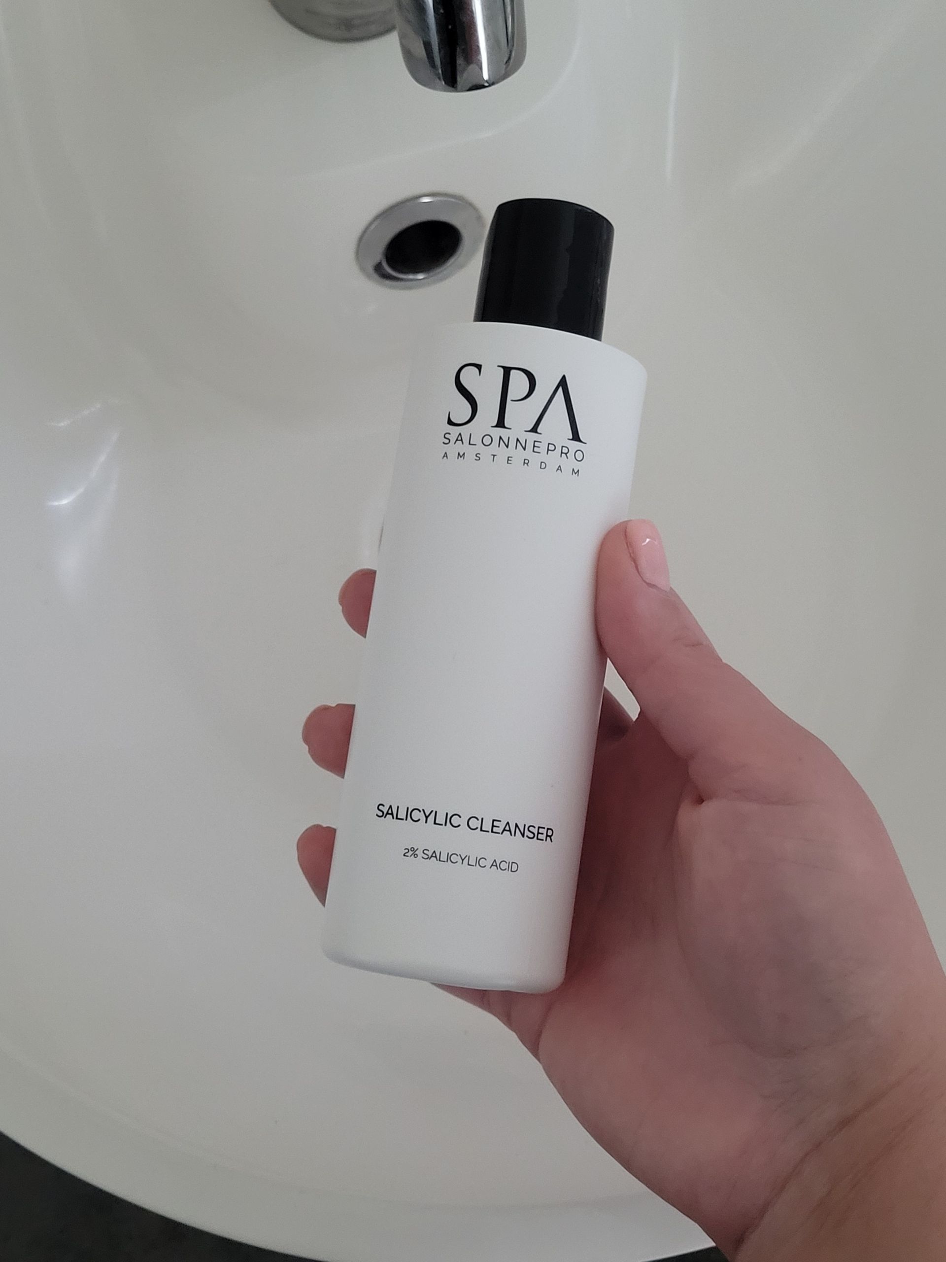 Witte fles SPA Salonnepro Amsterdam salicylzuurreiniger. Zwarte dop, witte achtergrond.