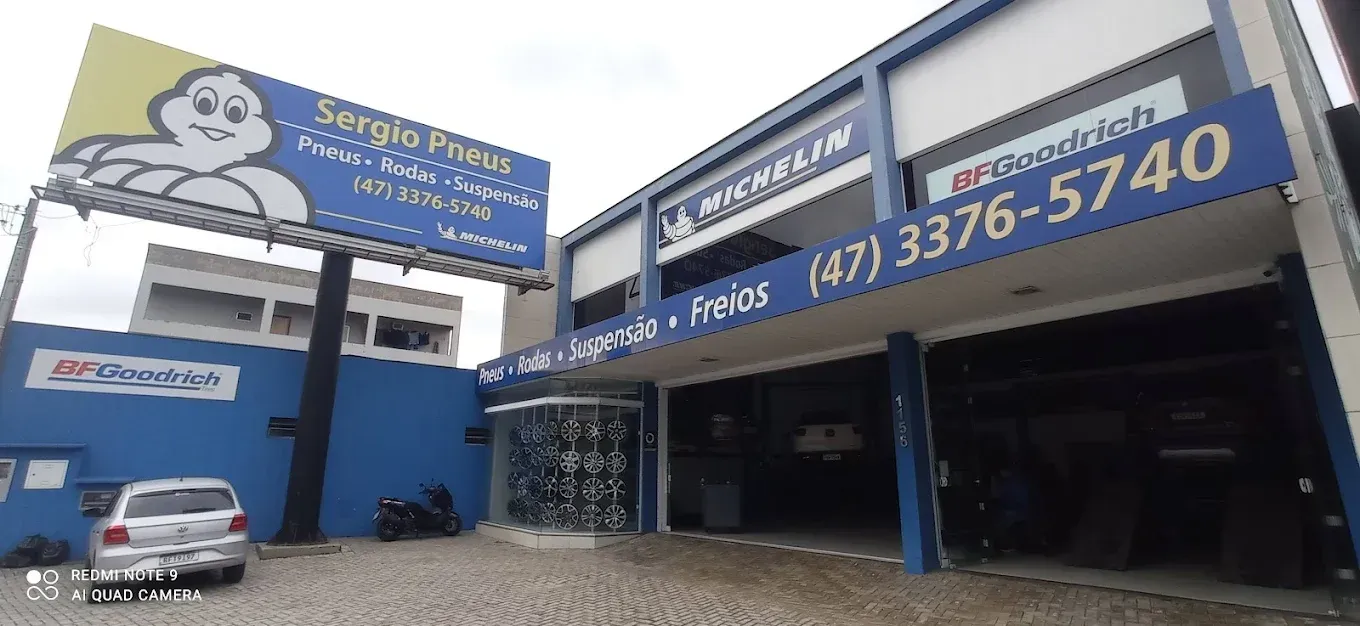 Fachada azul com grandes placas e estacionamento sob um céu nublado.