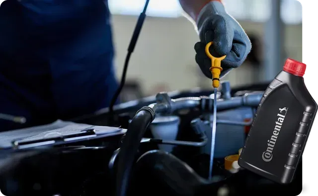 Uma mão enluvada verifica o nível de óleo de um carro com uma vareta, ao lado de uma garrafa de óleo de motor Continental.