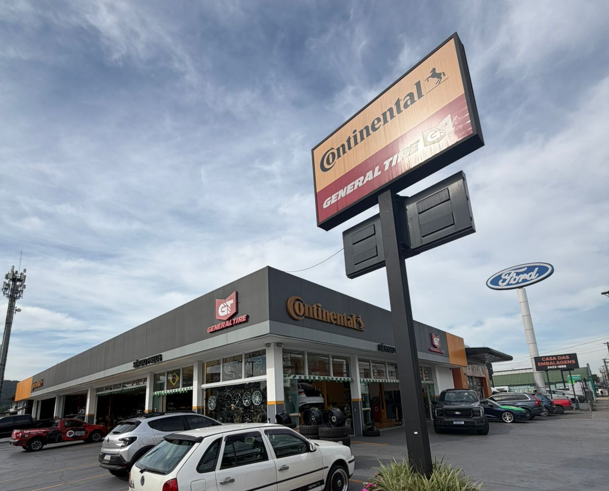 Exterior de uma loja da Continental Tire em um estacionamento com vários carros estacionados e placas de sinalização.