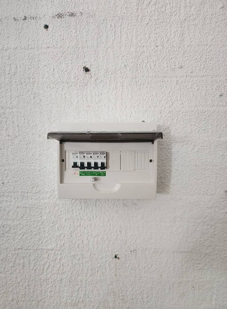 White Electrical Fuse Box Mounted on a Textured White Wall — Wetzel Electrical in Dapto, NSW