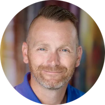 A man with a beard and a blue shirt is smiling in a circle.