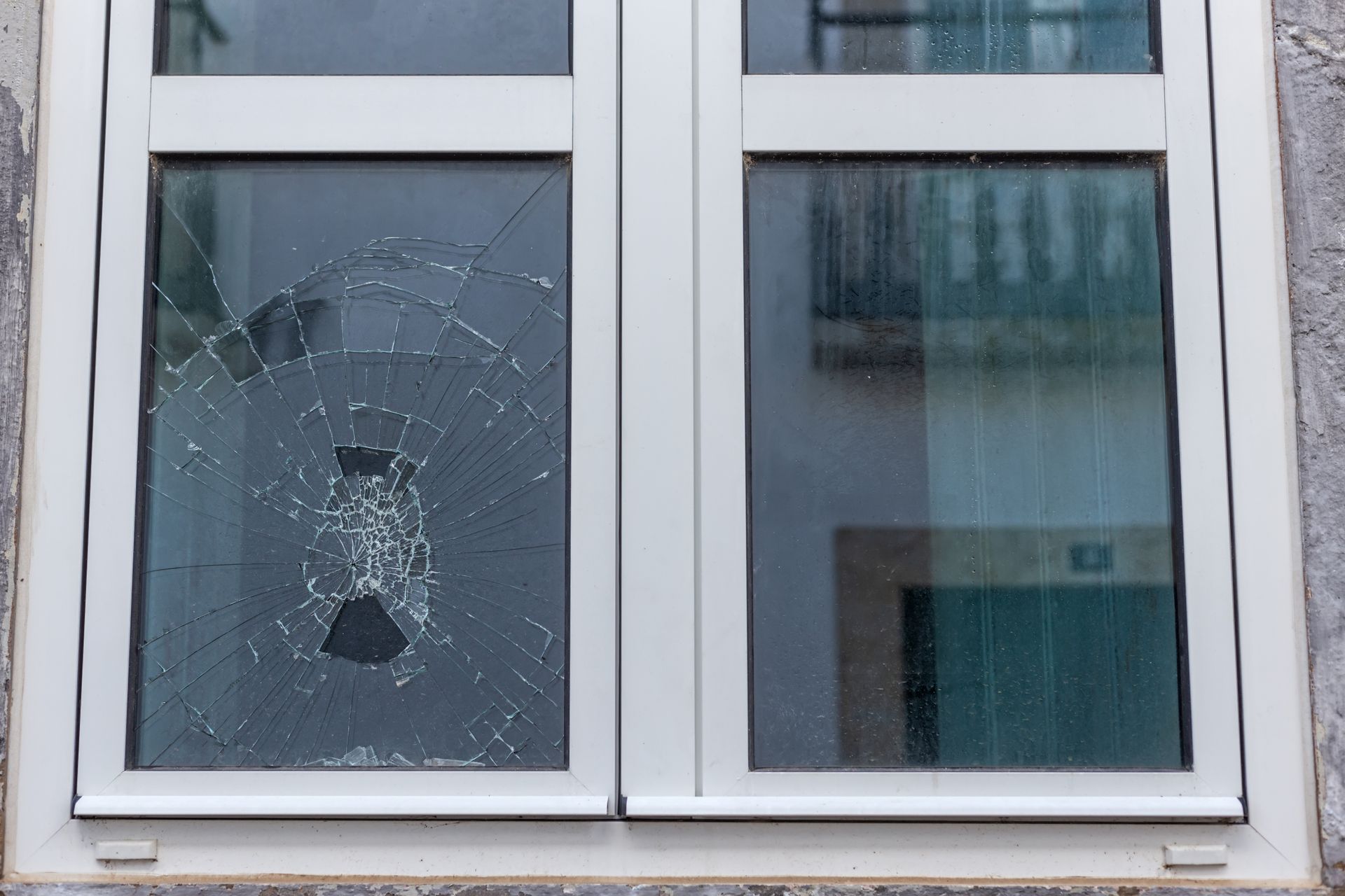 A broken window with a hole in it on a building.