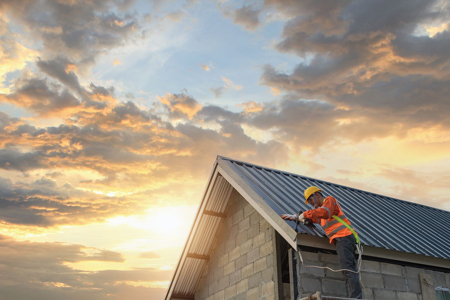 A construction worker is working on the roof of a house.