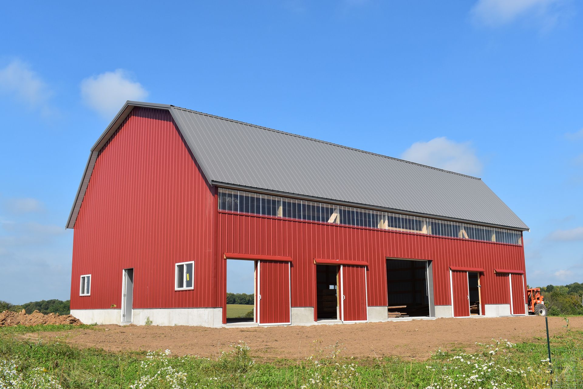 A large red barn is sitting in the middle of a grassy field