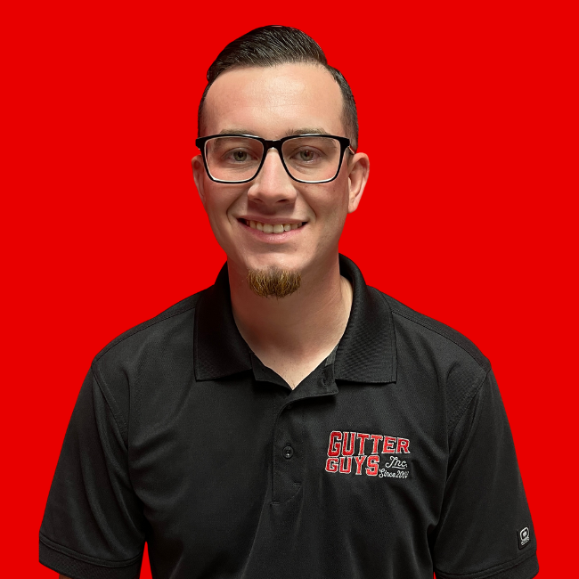 Smiling man in glasses and black polo shirt against a bright red background