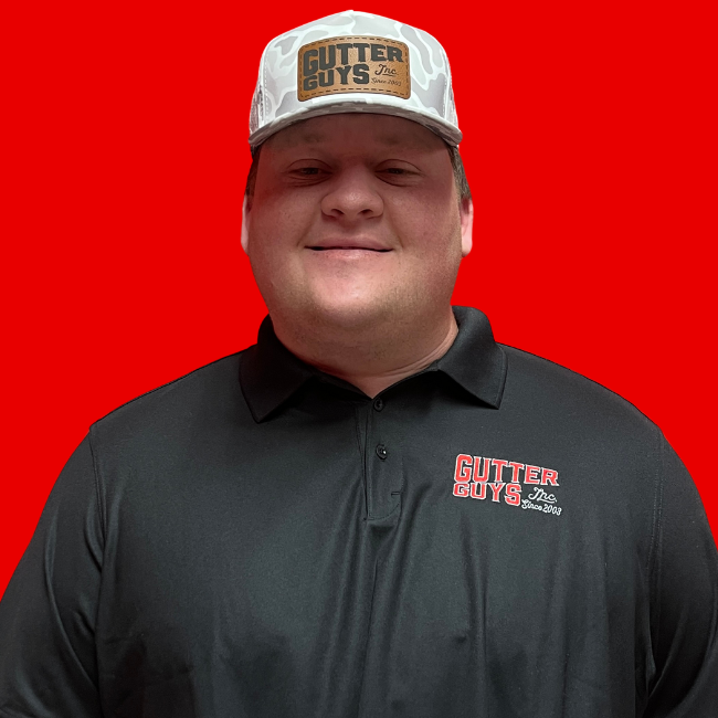 Smiling person in a black polo and logo cap against a bright red background.