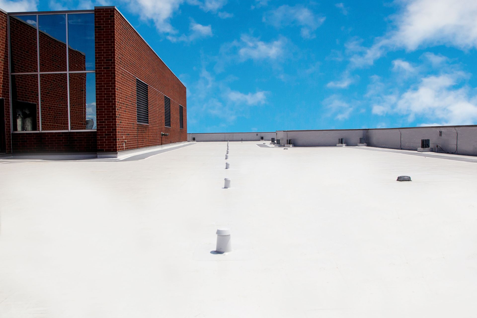 Snow-covered rooftop beside a red brick building under a blue sky.