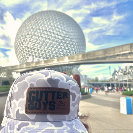 Gray camo hat with “BUTTER GUYS” logo in foreground at Epcot’s Spaceship Earth