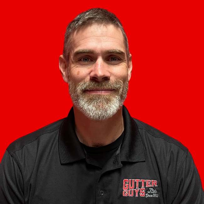 Smiling man in black collared shirt with Gutter Cover logo, against a solid red background