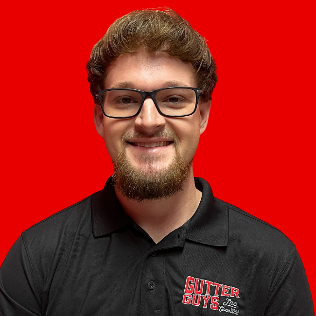 Smiling person in glasses and black polo shirt against a bright red background