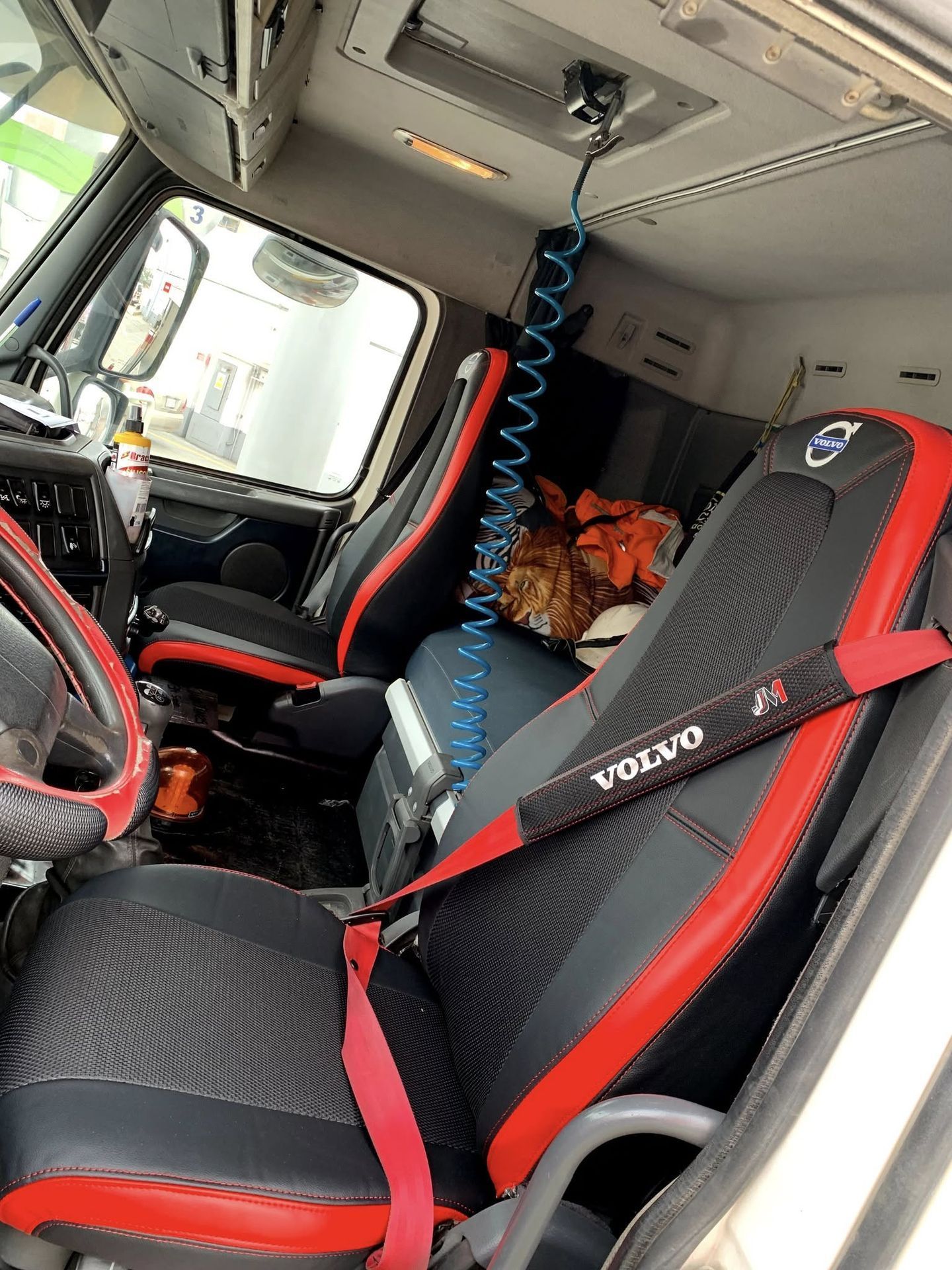 En el interior de la cabina de un camión Volvo con dos asientos negros y rojos