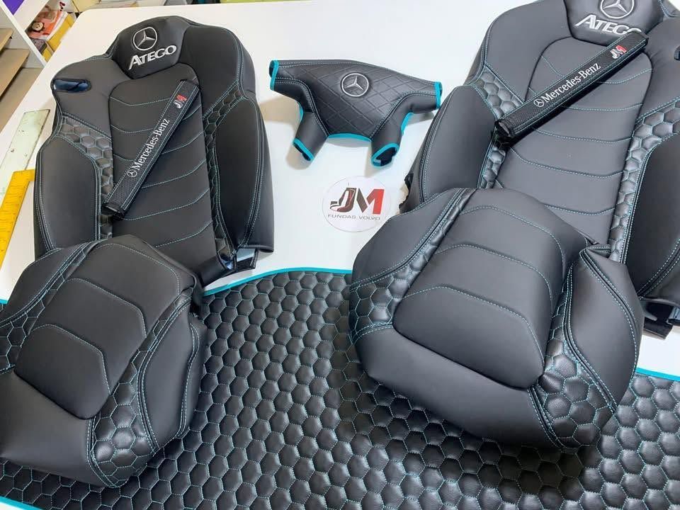 Dos fundas negras personalizadas para asientos de coche con reposacabezas a juego y un ribete azul sobre una alfombrilla.