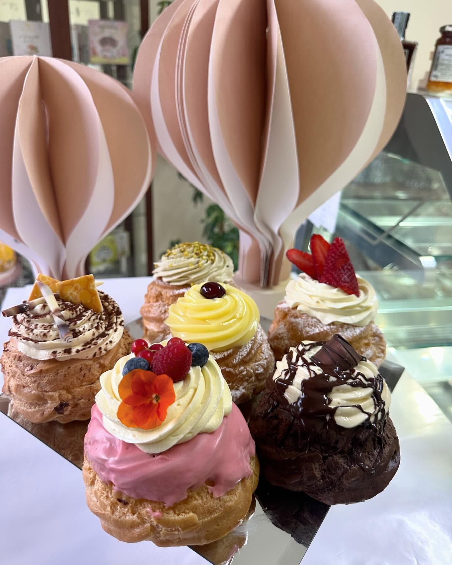Un mucchio di cupcakes sono appoggiati su un tavolo con mongolfiere di carta sullo sfondo