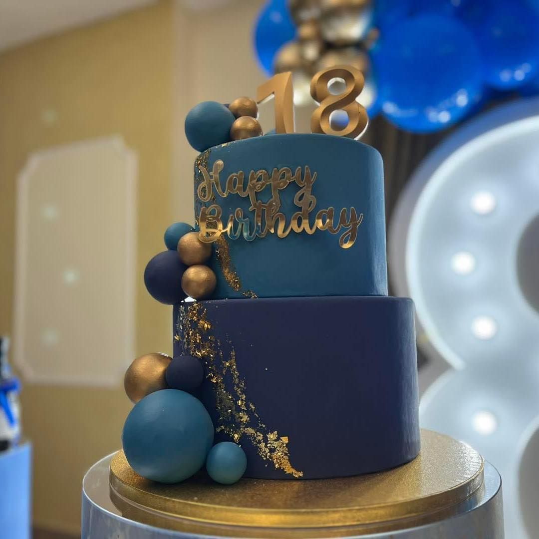 Una torta di compleanno blu e oro con il numero 18 in cima