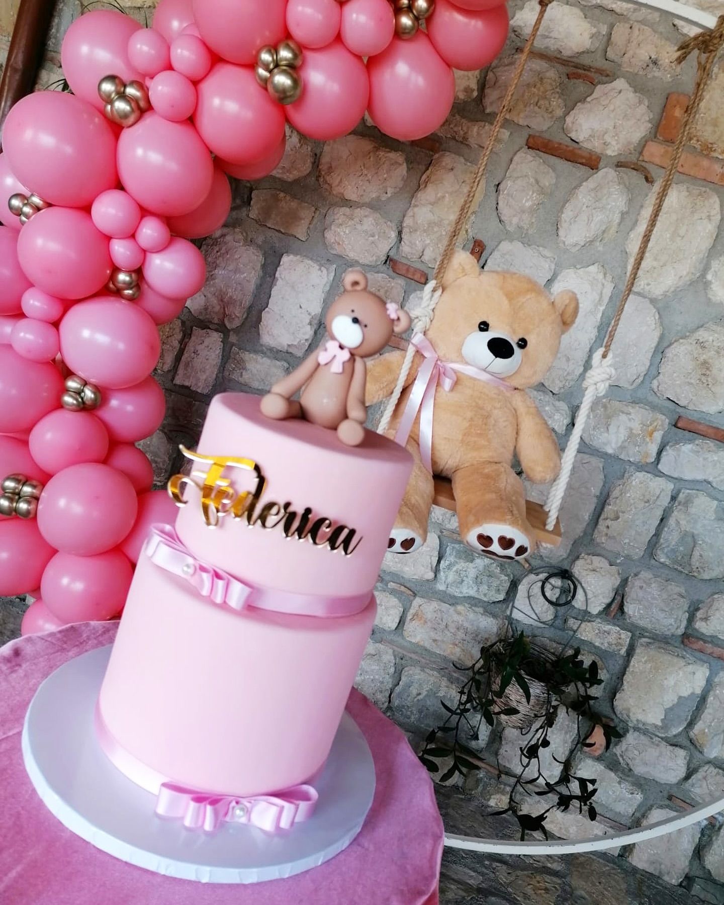 Una torta rosa con un orsacchiotto sopra.